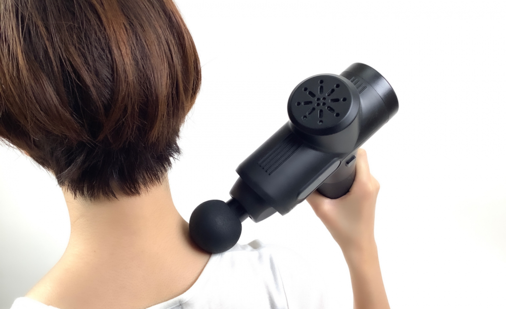 マッサージガンで肩をケアする女性